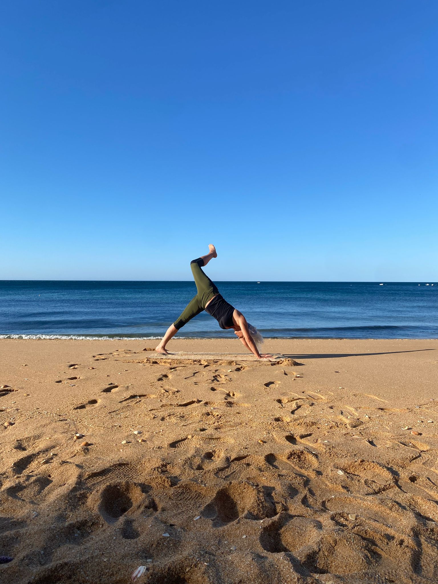 Gudrun Docherty in a downward-facing dog variation on the beach