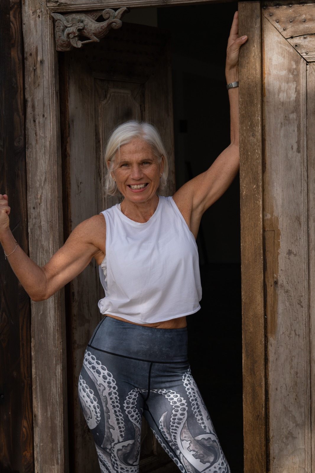 Gudrun Docherty standing in a doorway, arms raised, smiling